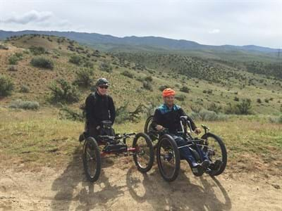 Two adaptive cycle users stopped on a foothills trail overlooking the City of Boise.