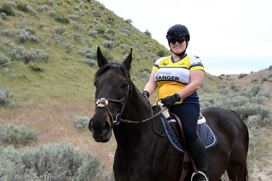 Woman on horseback with yellow and white jersey that says "Ranger".